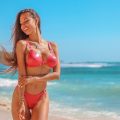 woman in red bikini standing on beach during daytime