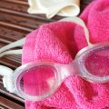 Swim goggles, towel, and a swim cap are displayed
